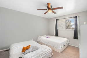 Bedroom with ceiling fan and light colored carpet