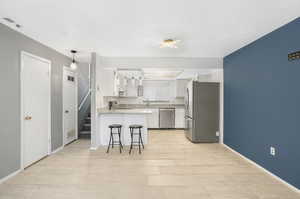 Kitchen with a breakfast bar, sink, white cabinetry, stainless steel appliances, and kitchen peninsula