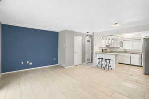 Kitchen with stainless steel appliances, sink, light stone counters, white cabinets, and a breakfast bar