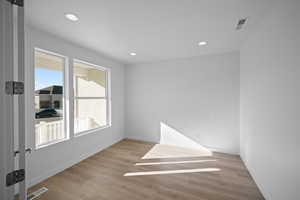 Empty room with light hardwood / wood-style floors and a textured ceiling