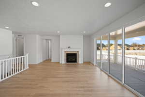 Unfurnished living room with a textured ceiling, light hardwood / wood-style flooring, and a tiled fireplace