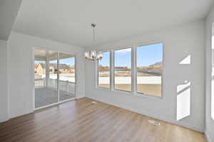 Unfurnished dining area with hardwood / wood-style floors, a textured ceiling, and an inviting chandelier