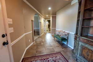 Corridor featuring crown molding and light tile patterned flooring