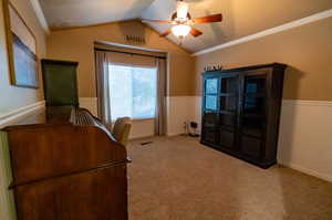 Unfurnished office featuring ceiling fan, vaulted ceiling, crown molding, and carpet