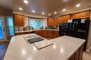 Kitchen featuring sink, black appliances, and tasteful backsplash