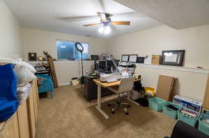 Carpeted office featuring a textured ceiling and ceiling fan