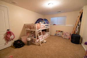 Bedroom featuring a textured ceiling and light carpet