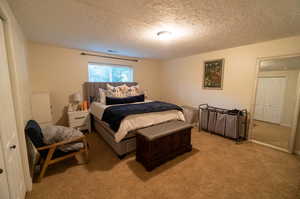 Bedroom featuring a textured ceiling and light colored carpet