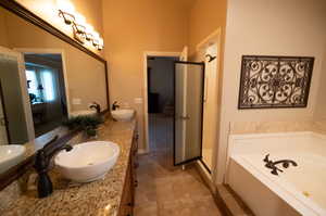 Bathroom featuring plus walk in shower, dual bowl vanity, and tile patterned floors