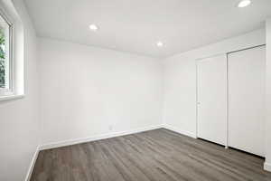 Unfurnished bedroom with a closet, hardwood / wood-style floors, and multiple windows