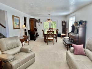 Living room featuring light carpet, a notable chandelier, connected to formal dining room