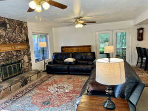 Family room with a textured ceiling, ceiling fan, a healthy amount of sunlight, and a fireplace