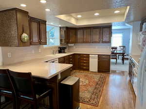 Kitchen featuring light laminate flooring, sink, kitchen bar, and a textured ceiling