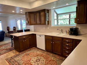 Kitchen featuring sink, light laminate flooring, dishwasher, compactor, and a wealth of natural light