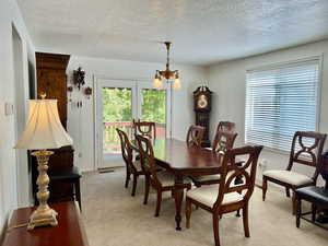 Formal Dining space featuring a notable chandelier, a textured ceiling, and light carpet. French doors out to deck.