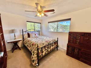 Carpeted bedroom featuring ceiling fan and a textured ceiling