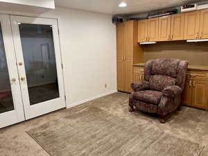 Basement craft / workshop room featuring french doors to garage, and carpet flooring