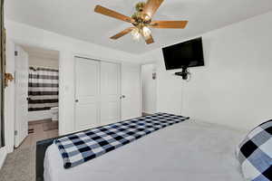 Tiled bedroom with ceiling fan, a closet, and ensuite bath