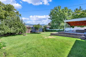 View of yard featuring a mountain view, a trampoline, and a patio area