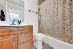 Full bathroom featuring shower / bath combination with curtain, toilet, tile patterned flooring, and vanity