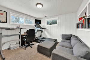 Carpeted home office featuring a textured ceiling