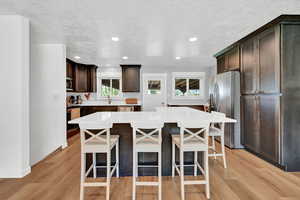 Kitchen featuring light wood-type flooring, a center island, stainless steel appliances, and a breakfast bar area