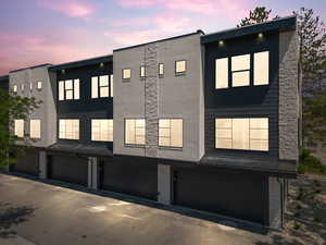 View of front of house with stucco siding, a garage, and stone siding