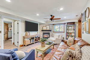 Living room featuring ceiling fan, a fireplace, and light hardwood / wood-style floors