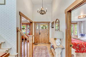 Foyer entrance featuring a high ceiling, plenty of natural light, a chandelier, and light wood-type flooring