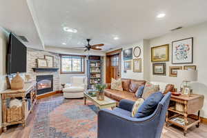 Living room featuring ceiling fan, a fireplace, and light hardwood / wood-style flooring