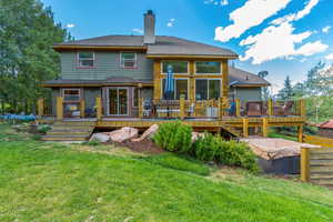 Rear view of house with a lawn and a deck