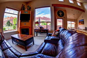 Living room with vaulted ceiling with beams and fireplace and beautiful views of Moab Rim.