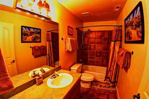 Full bathroom with vanity, tile patterned floors, toilet, and shower / tub combo and custom lighting