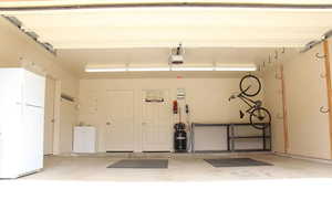 Garage featuring extra refrigerator, workbench, sink and air compressor