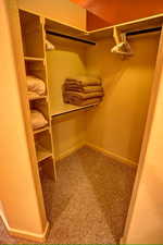 Primary walk-in closet with bulit-in closet shelving and carpet