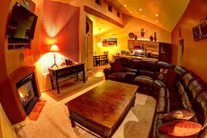 Living room at night featuring high vaulted ceiling and fireplace