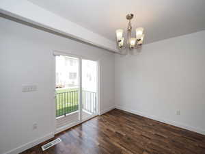 Spare room with an inviting chandelier and wood-type flooring