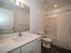 Full bathroom with shower / bath combination with curtain, toilet, vanity, and wood-type flooring