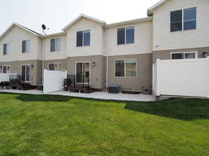 Rear view of property featuring a patio area, central AC, and a lawn