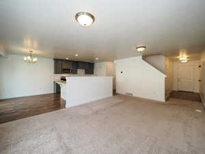 Unfurnished living room with carpet and an inviting chandelier