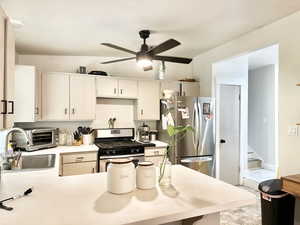 Kitchen featuring sink, appliances with stainless steel finishes, ceiling fan, kitchen peninsula, and lofted ceiling