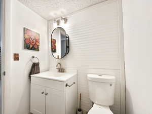 Bathroom featuring a textured ceiling, vanity, and toilet