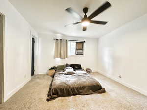 Bedroom with ceiling fan, light carpet, and cooling unit