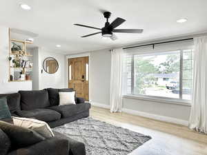 Living room with ceiling fan and light hardwood / wood-style floors