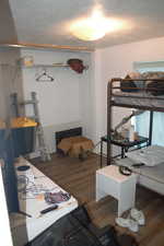 Bedroom with a textured ceiling and wood-type flooring