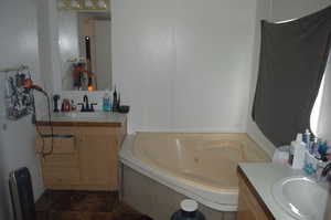 Bathroom with tile patterned floors, vanity, and a tub to relax in