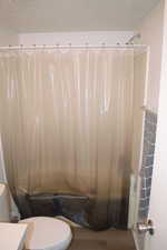 Bathroom with a textured ceiling, toilet, and hardwood / wood-style flooring