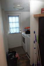 Laundry area featuring washing machine and dryer, a textured ceiling, and dark tile patterned flooring