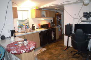 Kitchen with sink, dark tile patterned floors, black appliances, and light brown cabinets