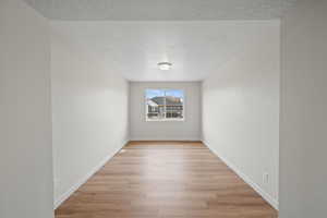 Unfurnished room with light hardwood / wood-style floors and a textured ceiling